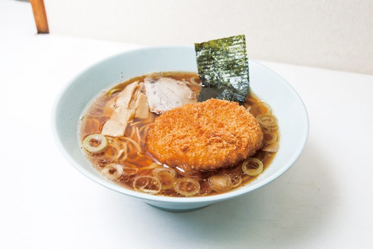 ↑コロッケラーメン（530円）。鶏と豚の骨でスープを取り、しょうゆ味の自家製だれと合わせた。細い縮れ麺はコロッケと不思議と合う