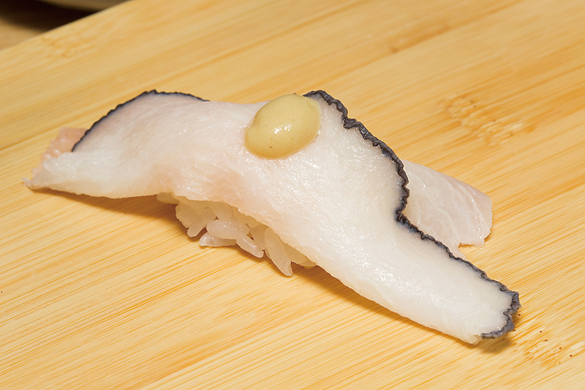 ↑鯨さずり/一貫(230円) くじらの舌を燻製(ベーコ ン)にして寿司ネタに。スモ ークされ凝縮した脂のうまみ がじわじわ広がる。トッピ ングの練りがらしが味のアクセントとなって、たまらなくうまい