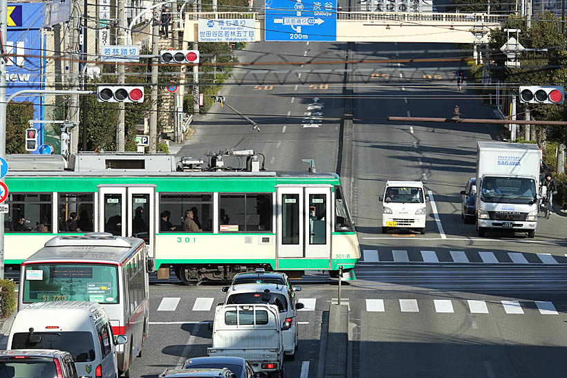 ↑世田谷線と環七通りが交差する若林踏切。若林駅のすぐ横を通る環七通りをゆっくりと電車が横切る