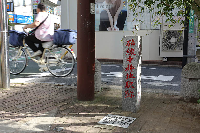 ↑ “玉電”砧線の中耕地駅跡に残る石碑。後ろの道路が元の線路跡だ。二子玉川駅から徒歩5分ほど