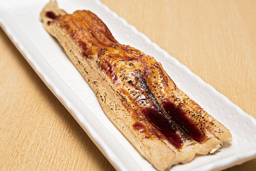 ↑一本穴子(615円) 特大サイズの穴子の下には、シャリが二貫。2人で食べられるようにという配慮だ。ふっくら煮たあと炙った穴子は、魚自体のうまみがきわめて濃厚だ