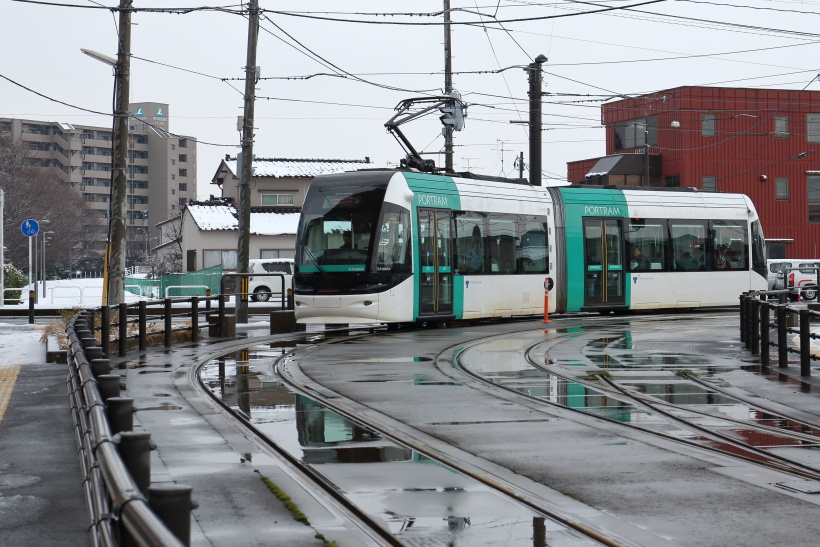 ↑奥田中学校前から富山駅北へ向け走る電車。左奥の遊歩道は以前、JR富山港線が走っていた路線跡だ