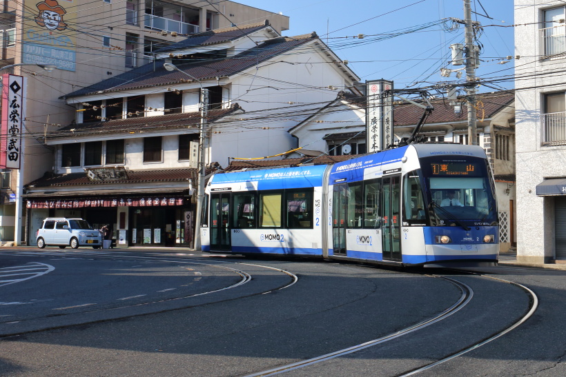 ↑中納言停留所付近を走る9200形MOMO2。後ろの店舗は岡山きびだんごの製造元「広栄堂武田」
