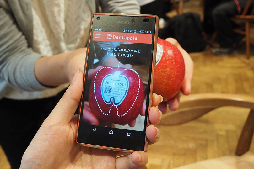 ↑デンタルチェックに使用する「Dentapple」と専用アプリを起動したスマートフォン。シールにプリントされたQRコードを撮影することでユーザーを識別します