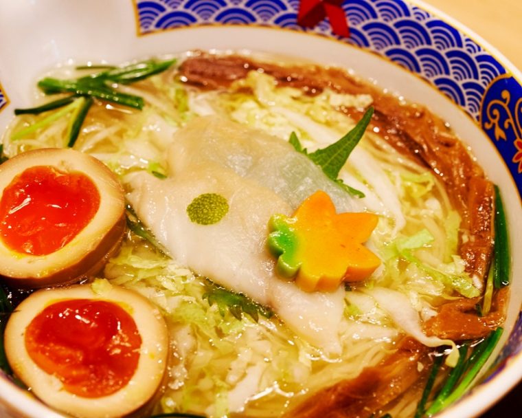 ↑ふぐだし潮らーめん美味玉入(¥1,150円)。たまり醤油で漬け込まれた玉子は、より色鮮やかに。また花の形をした麩には、四季に応じて色が変わるという粋な遊び心が込められています