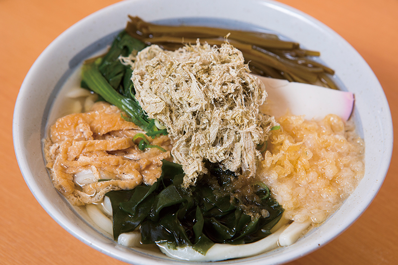 ↑かのやうどん(関西だし)(500円)。刻み揚げ、ほうれん草、とろろ昆布など7種類の具を トッピング。様々な味がつゆに溶け込んで、うまみがさ らに濃厚に