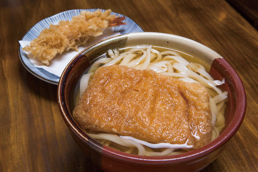 ↑きつねうどん+えび天…780円+350円。.甘く煮詰めた油揚げがのったきつねうどんも人気メニュー。お客のなかには、この油揚げがときどき無性 に食べたくなる人がいるという