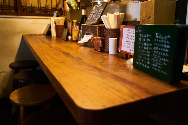 利田商店のカウンター。田中さんは酒が置いてあればラ飲みができる証で、特にビール以外の焼酎や日本酒、ワインがあればなおさらとか。さらにチャーシューやメンマ以外につまめるメニューもあれば申し分ないそうです