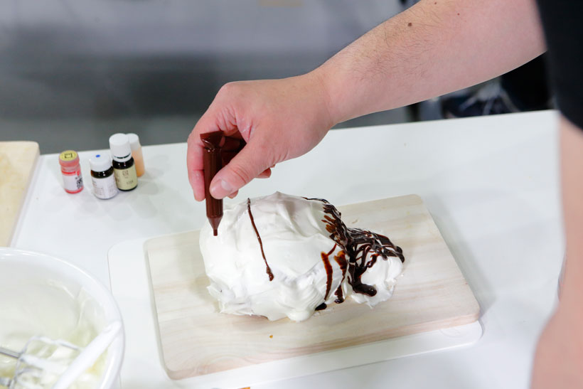 ↑生クリームをたっぷりのせた時点で「あ! 思いついた!」とチョコレートを使ってデコレーションを開始。できあがったのは、なんと外道選手の似顔絵ケーキでした