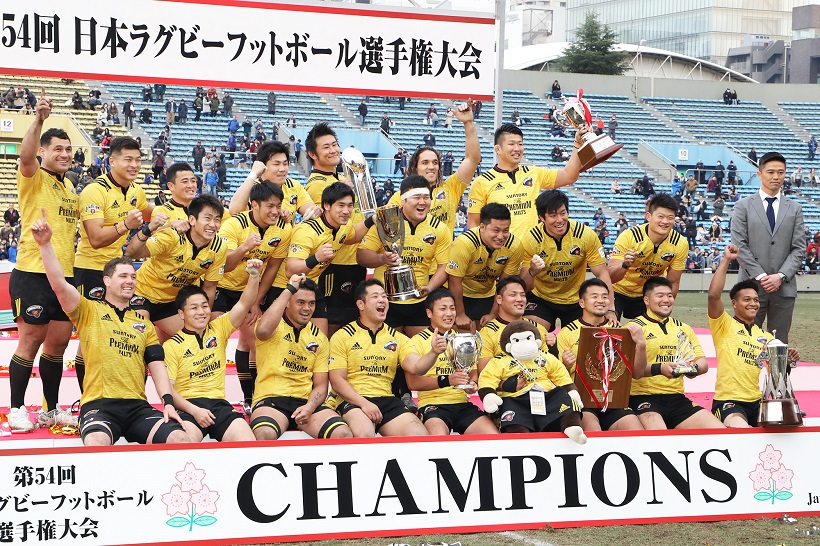 ↑日本選手権で優勝し、歓喜するサントリーのフィフティーンと沢木敬介監督(右端)。監督就任1年目で2冠を達成した