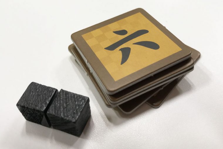 ↑「一」から「七」までの数字が書かれた『注力チップ』(「四」は2枚あり)。左の黒い立方体が『機密