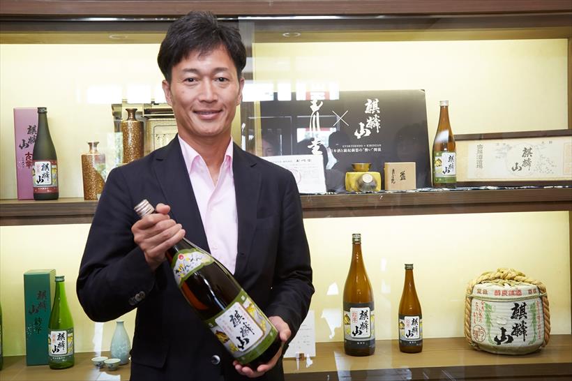 ↑看板商品の「麒麟山 伝統辛口」を手にする齋藤社長
