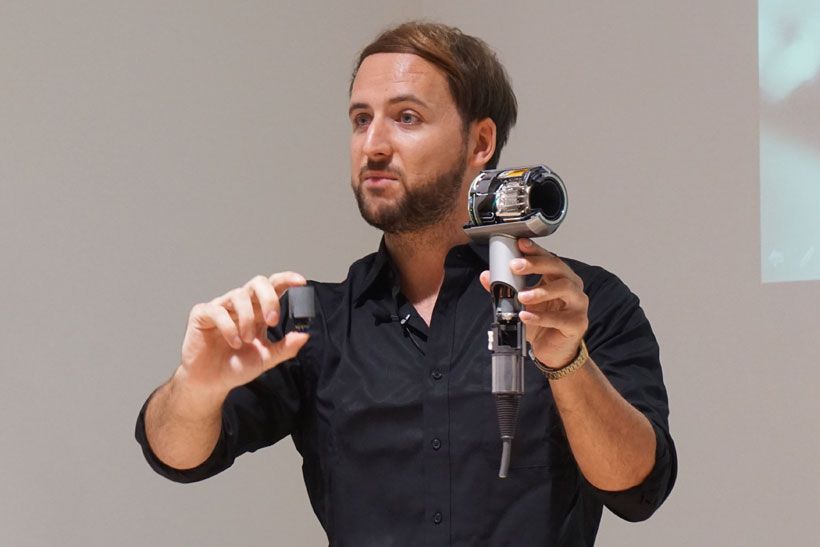↑Dyson Supersonic ヘアードライヤーのカットモデルを手にするウィリアムソン氏。「ハンドル部に小型高性能化したモーターを搭載したことで、業界に新しいイノベーションを生み出した」と力説します