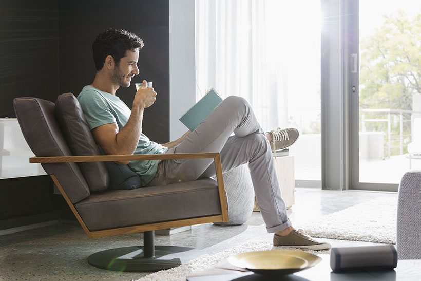 Man drinking tea and reading book in living room
