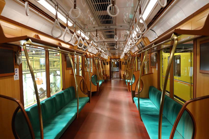 ↑車内の内装は木製色の化粧板をメインに。座席も通常車両の煉瓦柄に対して緑色のシートモケット、手すりは真鍮色とされている