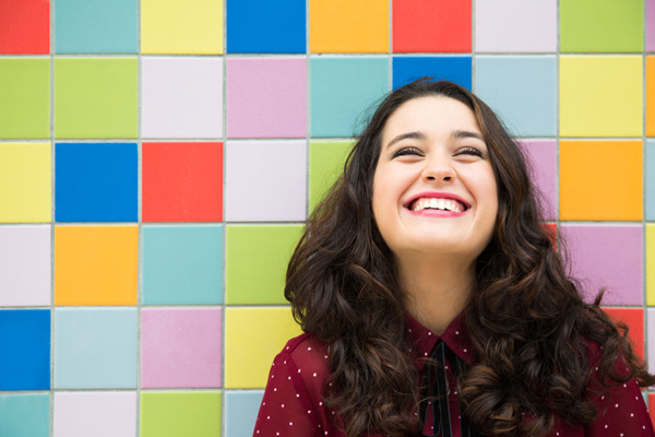 47210960 - happy girl laughing against a colorful tiles background. concept of joy