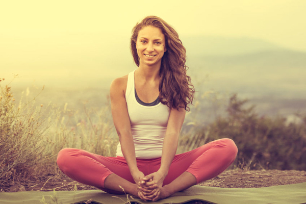 50413973 - young woman sits in yoga pose with city on background. freedom concept. calmness and relax, woman happiness. toned image