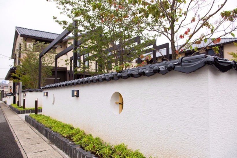 敷地の周囲に巡らされた土塀。瓦や月形に抜いて竹格子をはめ込んだ小窓や季節を彩る植栽が、そのコンセプトを伝えています