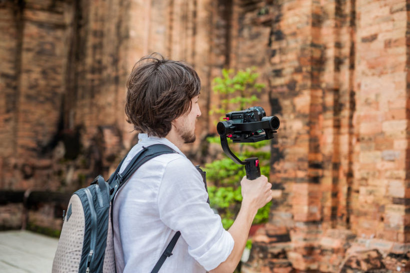 68529434 - man videographer shoots video in the electronic stabilizer, steadycam to shoot at po nagar cham tovers. digital technology concept. devices for shooting video concept. asia travel concept.