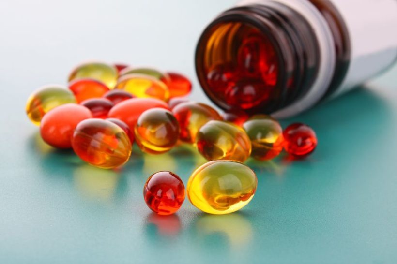 8721097 - red and yellow capsules of vitamins on a blue background
